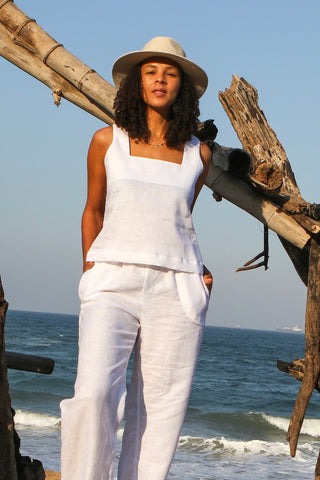 Woman in white linen outfit standing on a beach in Durban, South Africa, with ocean and sky in the background